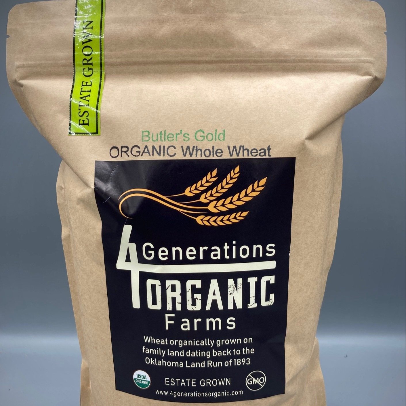 Brown paper bag of 4 Generations Organic Farms Butler's Gold Organic Whole Wheat, featuring a logo with wheat graphics and information about organic farming practices and historical significance dating back to the Oklahoma Land Run of 1893.